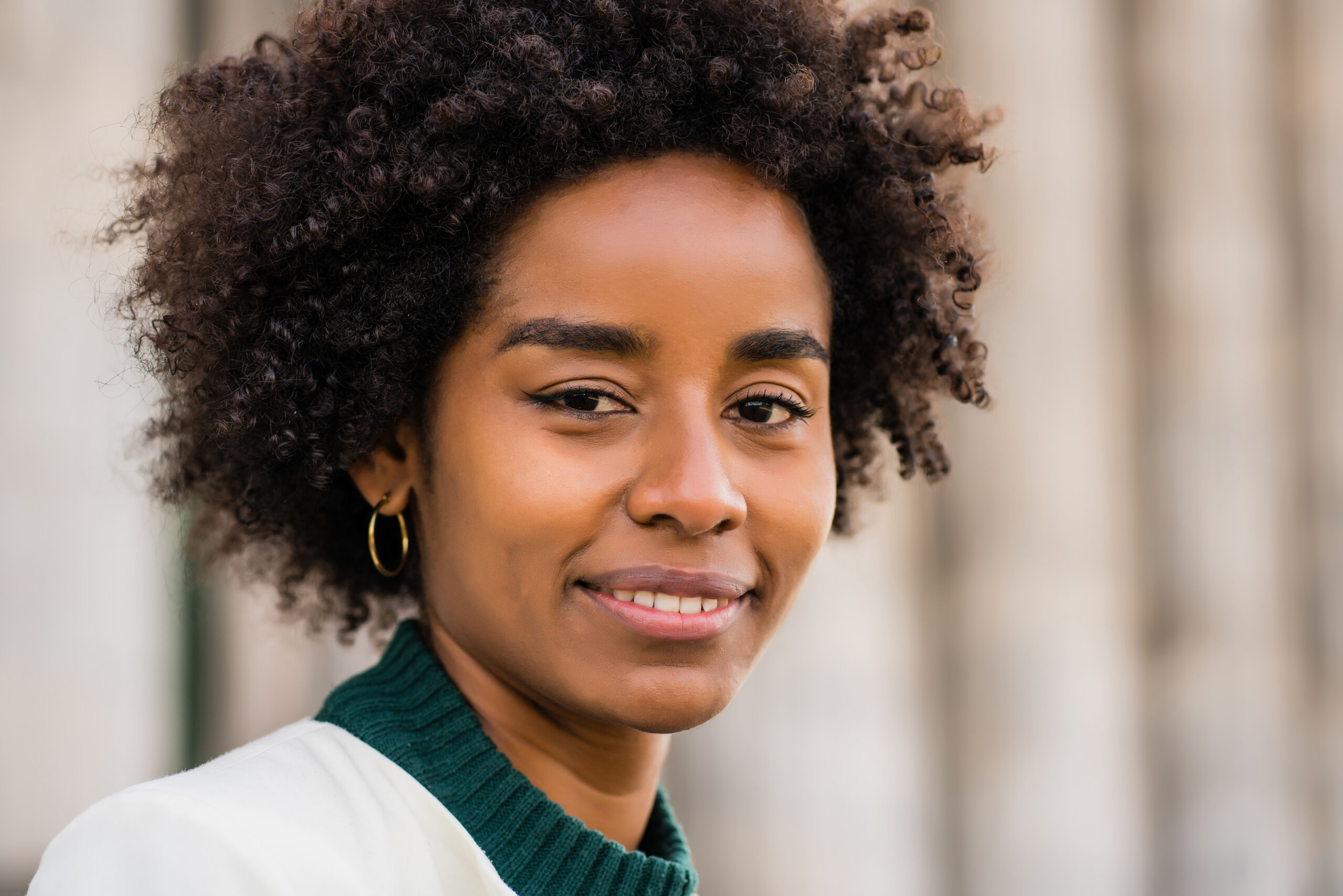 Close up of afro business woman smiling while standing outdoors on the street. Business and urban concept.